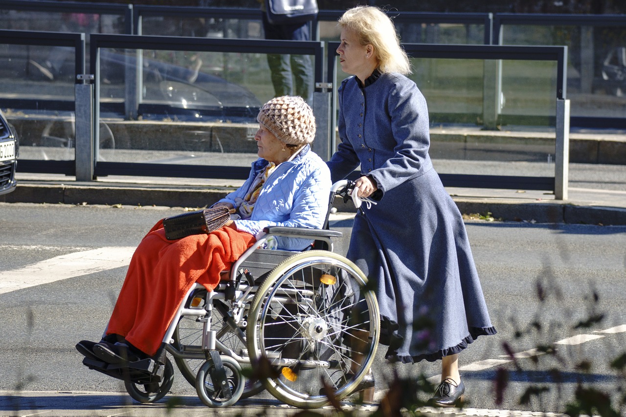 badante che assiste donna su sedia a rotelle